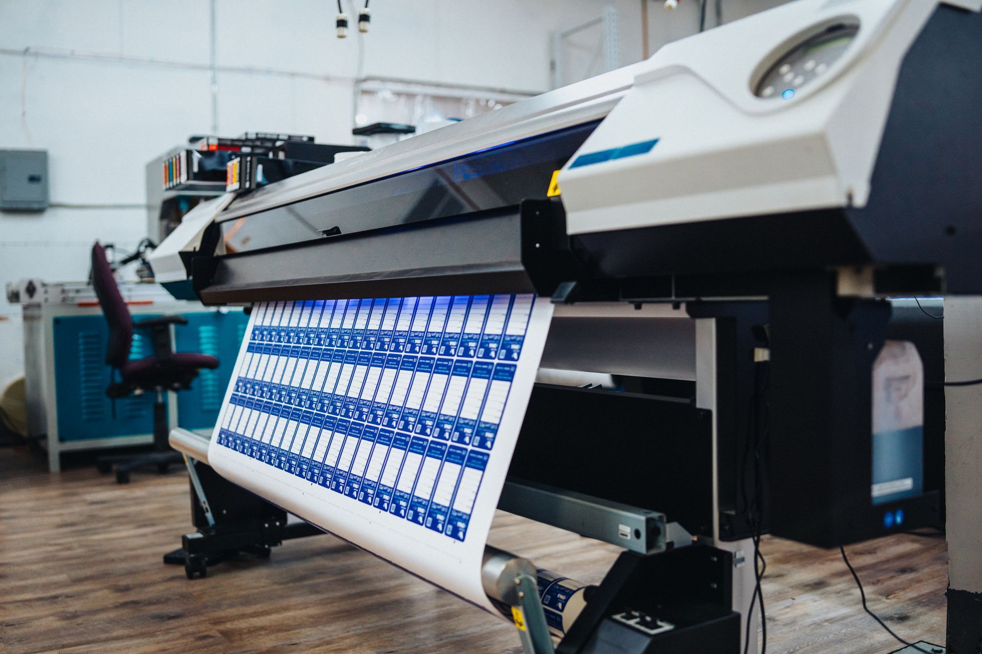Large printer producing blue and white labels in a print shop.