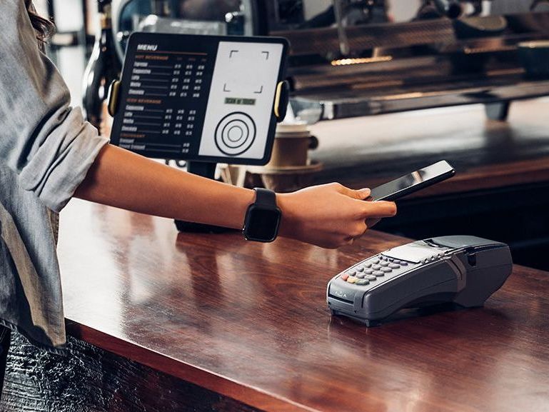 A woman is using a smart watch to pay for a meal in a restaurant.