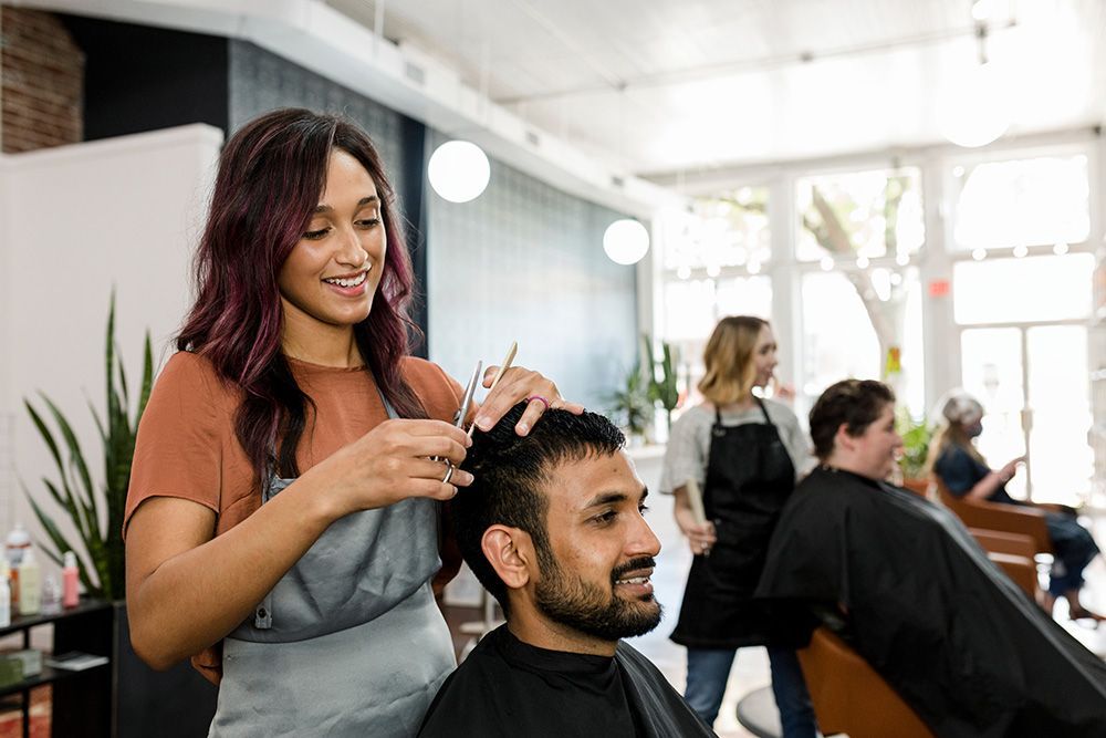 A woman is cutting a man 's hair in a salon.