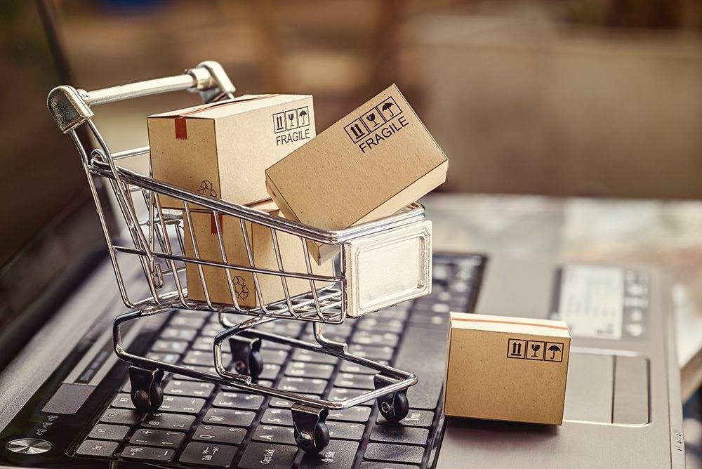 A shopping cart filled with boxes is sitting on top of a laptop keyboard.