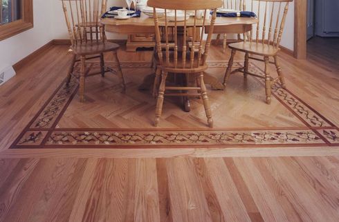 A dining room table with a border style hardwood floor.