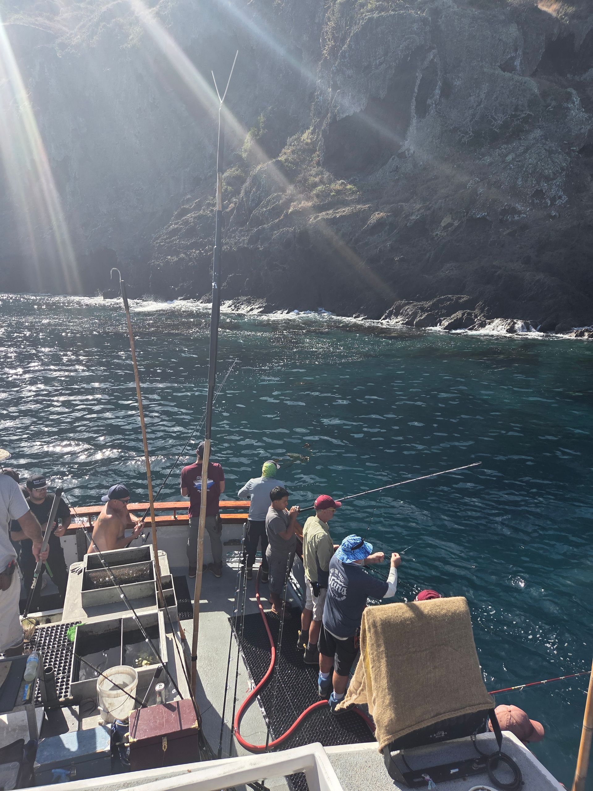 People fishing at night from a boat; dark water, fishing poles, bait wells, cool colors.