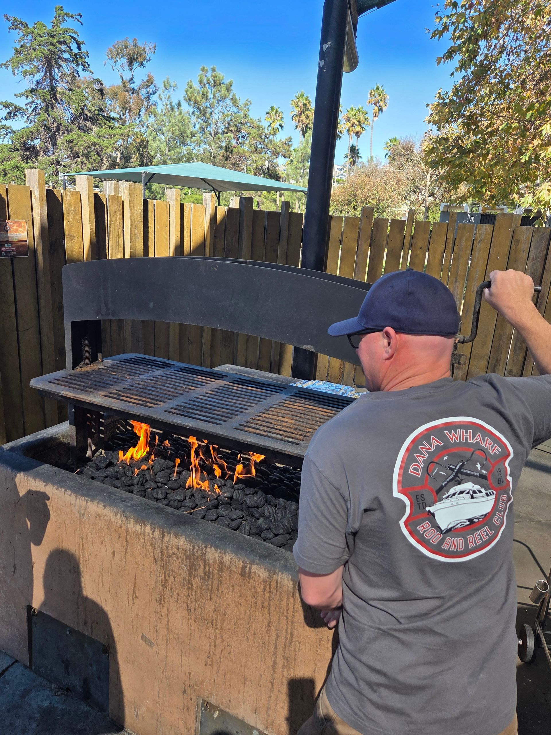 Man grilling over an open flame at an outdoor grill.
