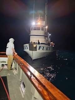 A person on a boat watches the fishing vessel
