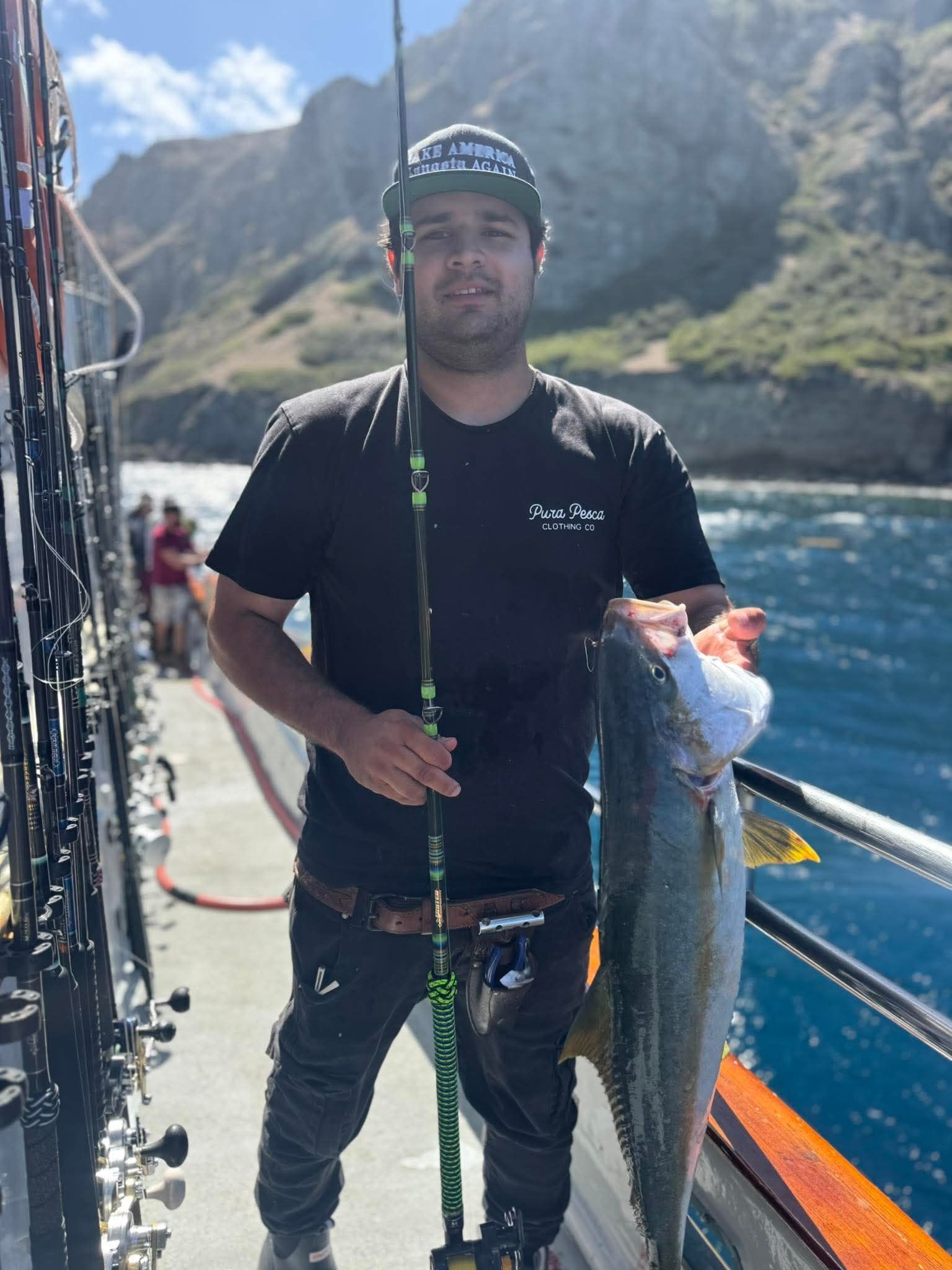 A person weighs a fish on a digital scale at 35.00 on a boat at sea.