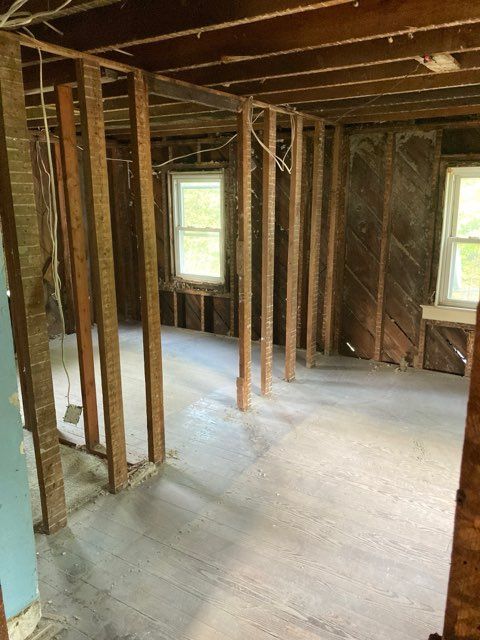 A room with wooden beams and a concrete floor in a house under construction.