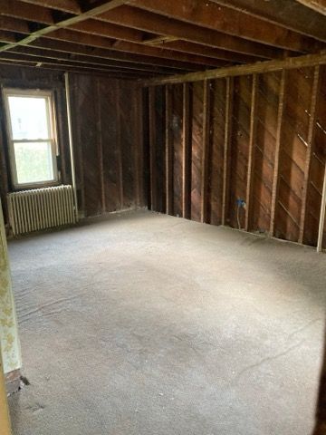 An empty room with wooden walls and a window.