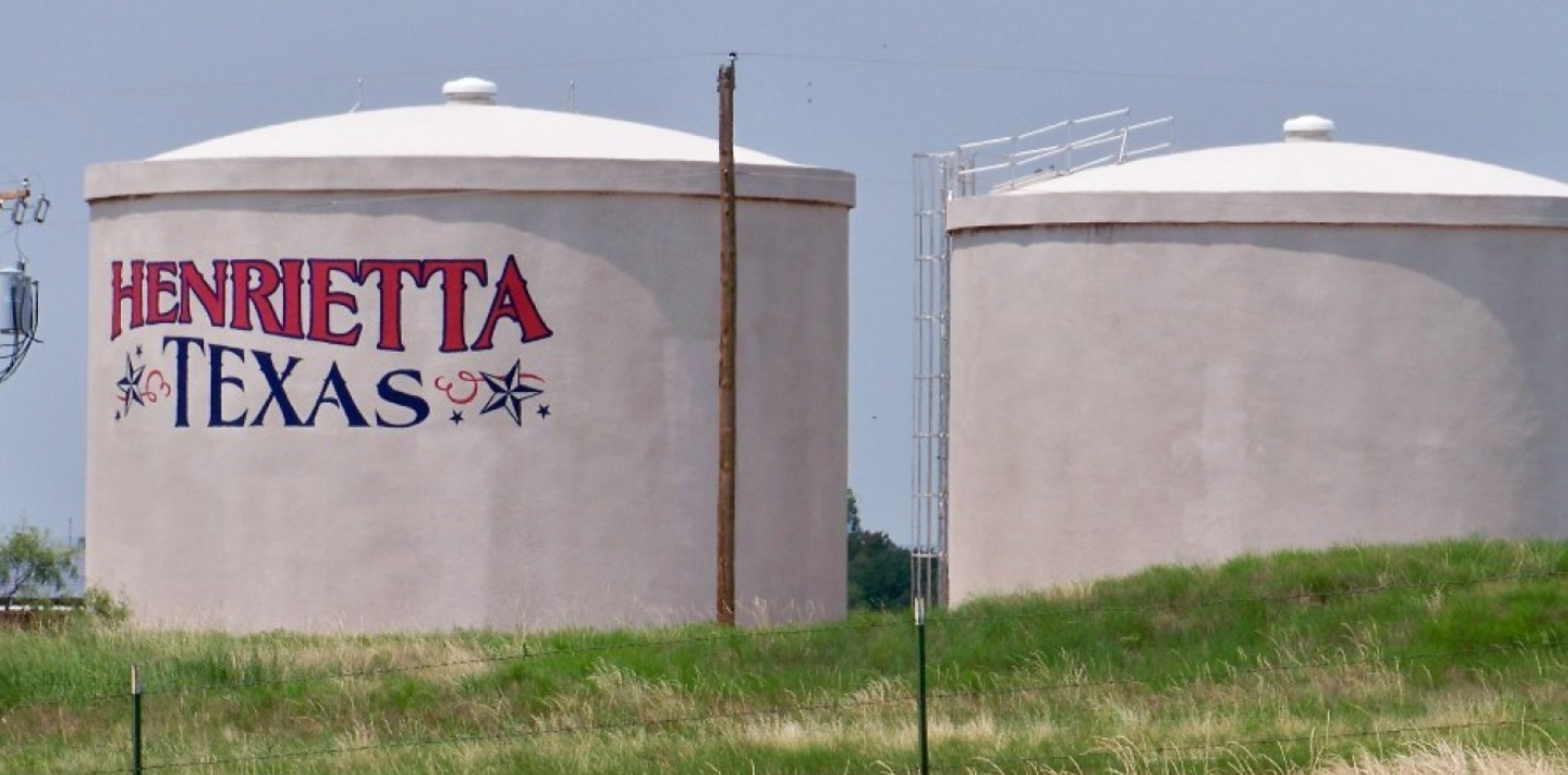 Two water towers in Henrietta, Texas; one is painted with the city's name.