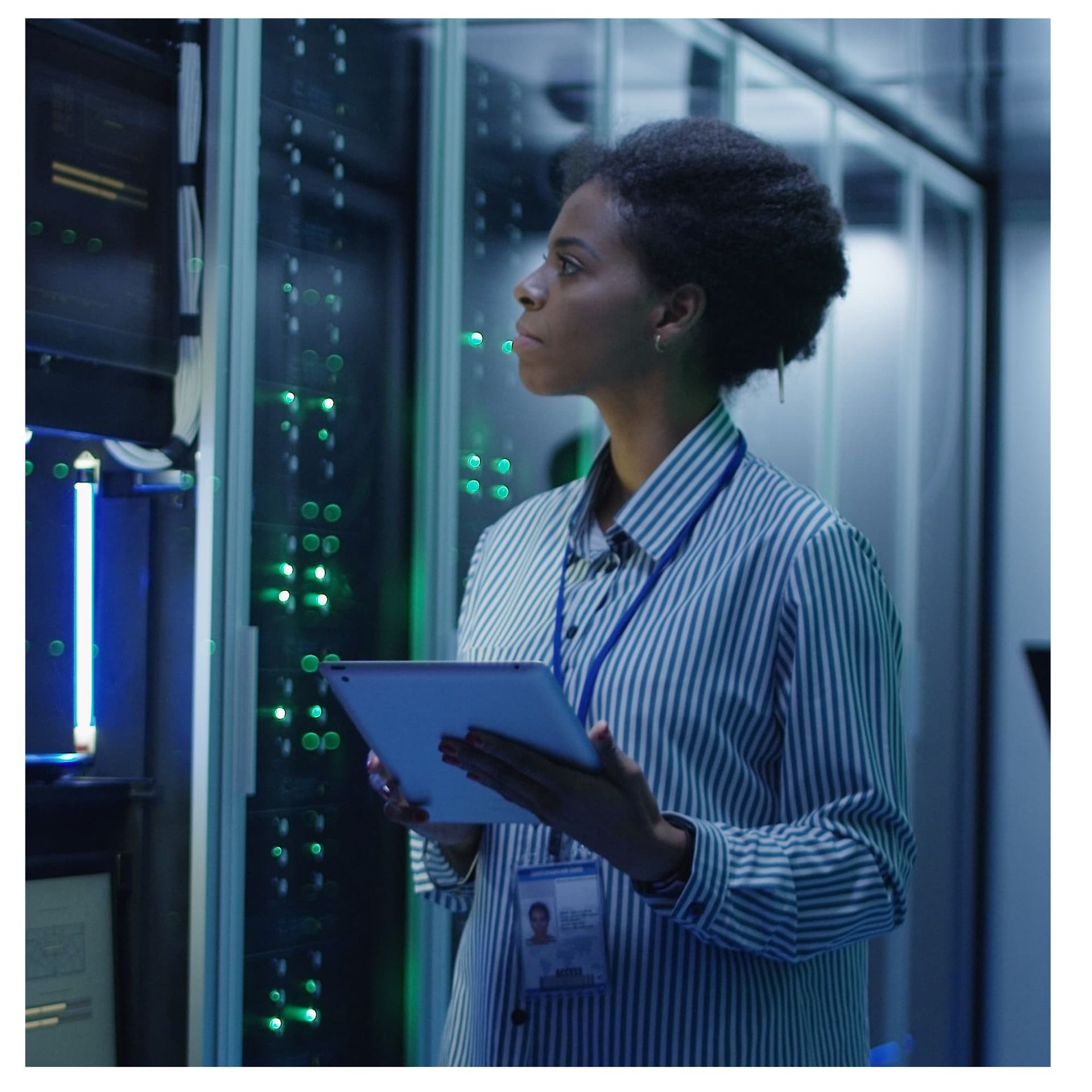 Two technicians examining a laptop in a server room with glowing network racks
