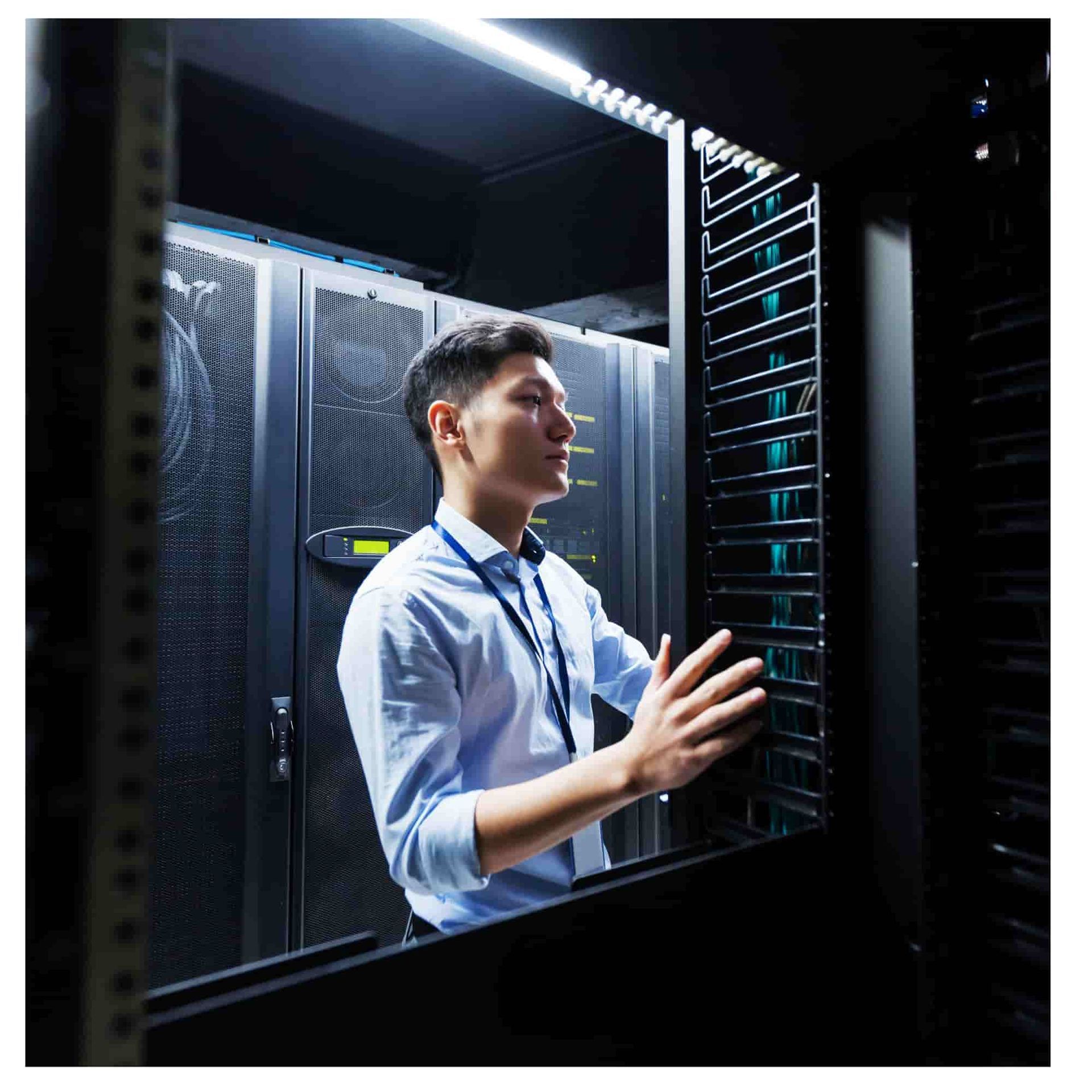 Two technicians examining a laptop in a server room with glowing network racks