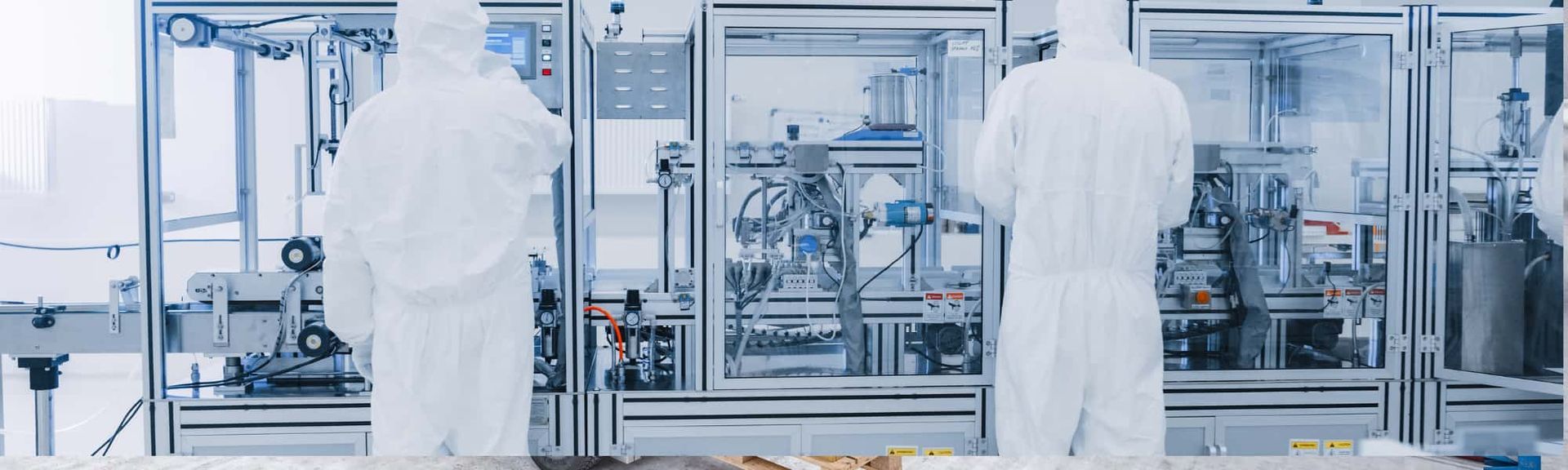 Two technicians in white lab coats working in a sterile industrial manufacturing lab