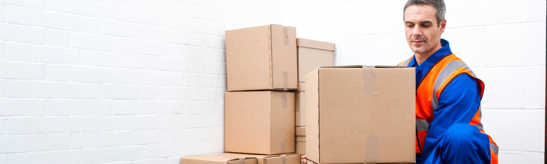 Delivery worker carrying cardboard boxes in a warehouse-like setting