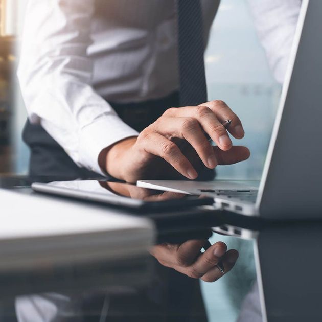 A man in a tie is typing on a laptop computer