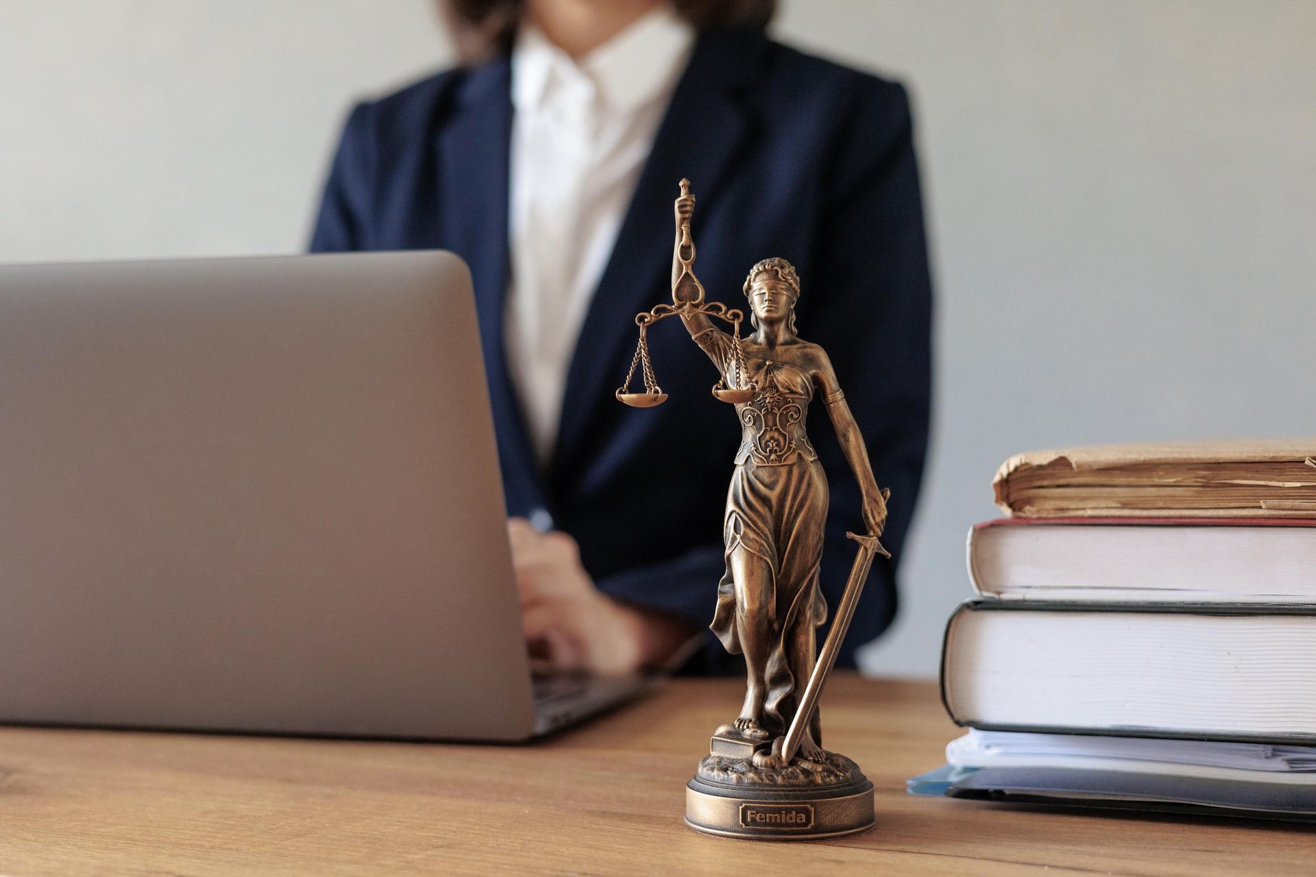 Lawyer’s desk with laptop, scales of justice figurine, and stacked law books