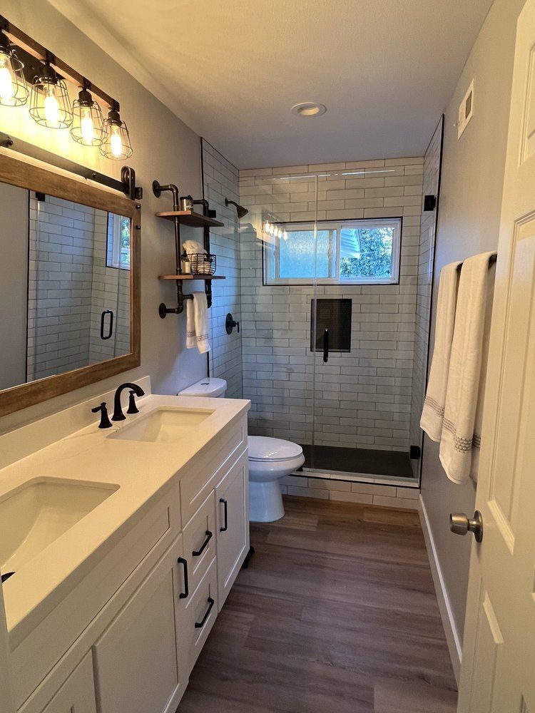 A bathroom with a toilet , sink , mirror and shower.