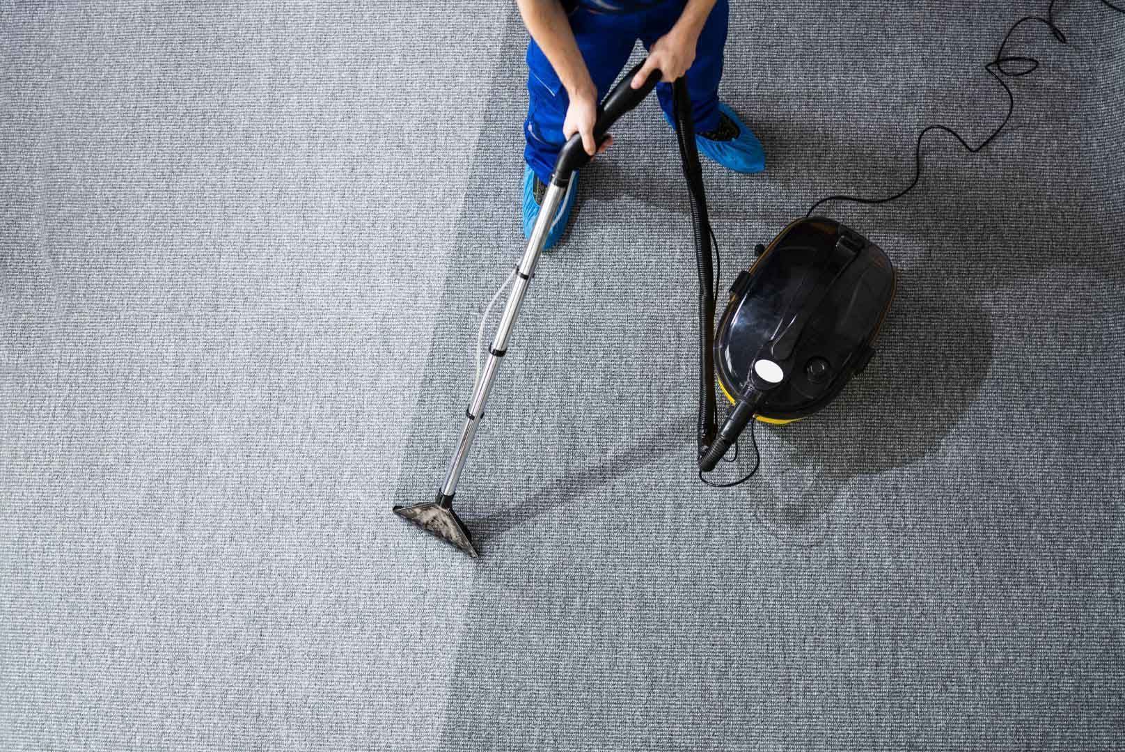 A person is using a vacuum cleaner to clean a carpet.