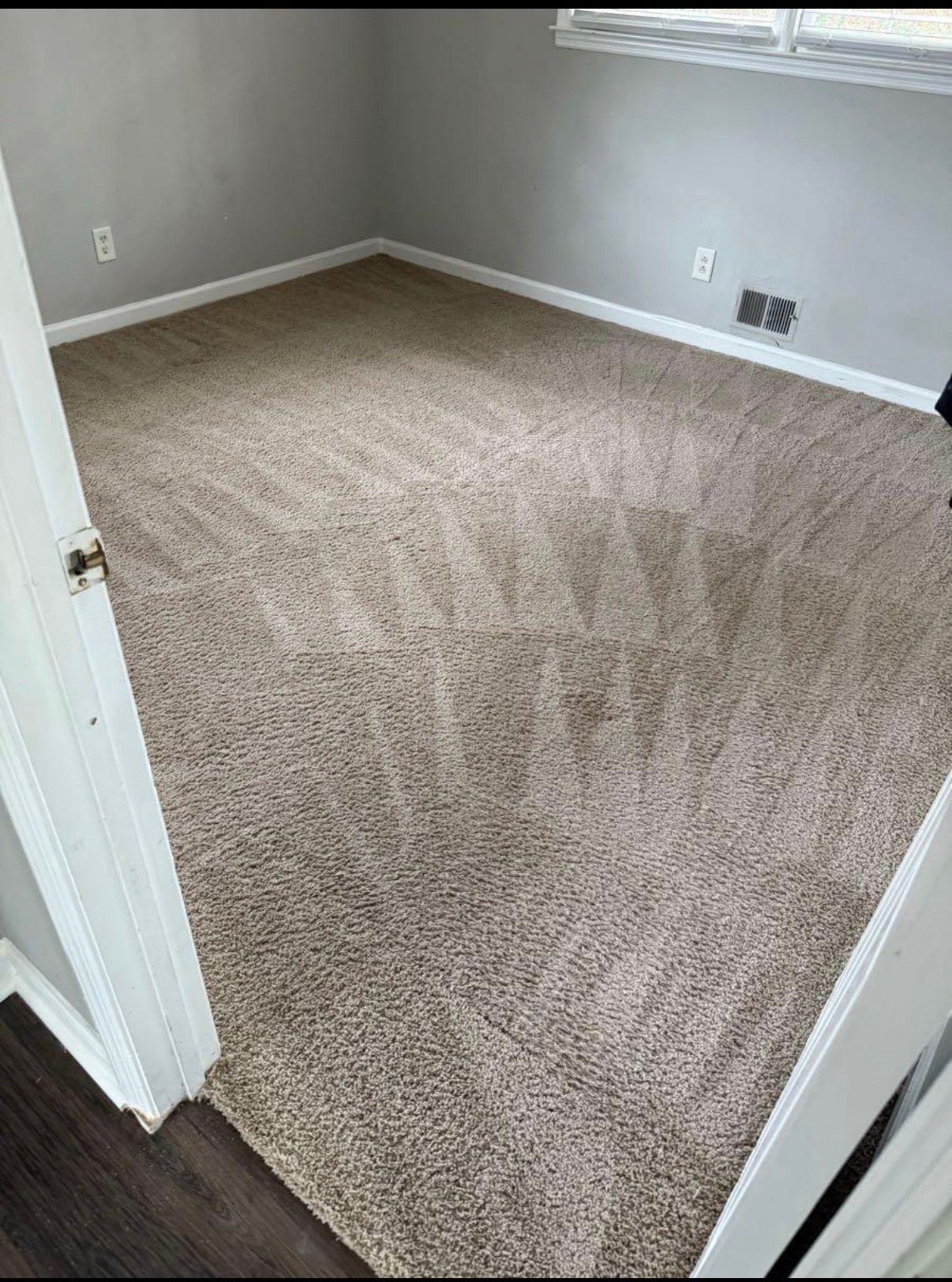 Empty room with beige carpet and gray walls, viewed from doorway.