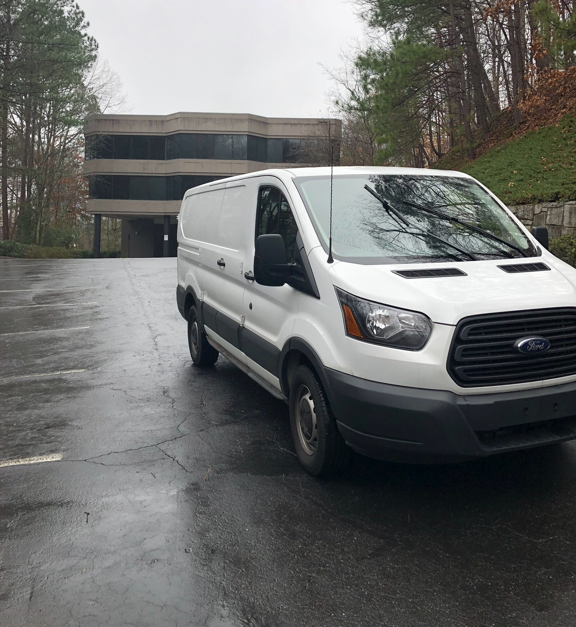 A white van is parked in a parking lot in front of a building.