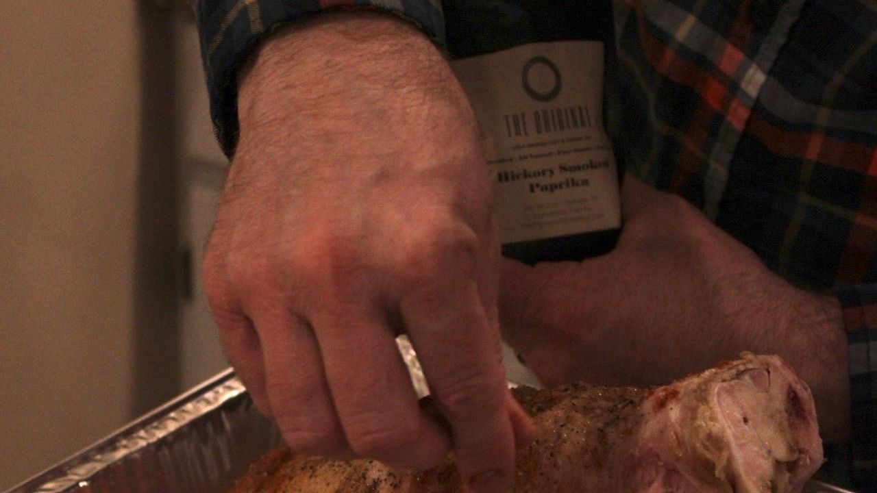 a person is holding a bottle of wine over a piece of meat
