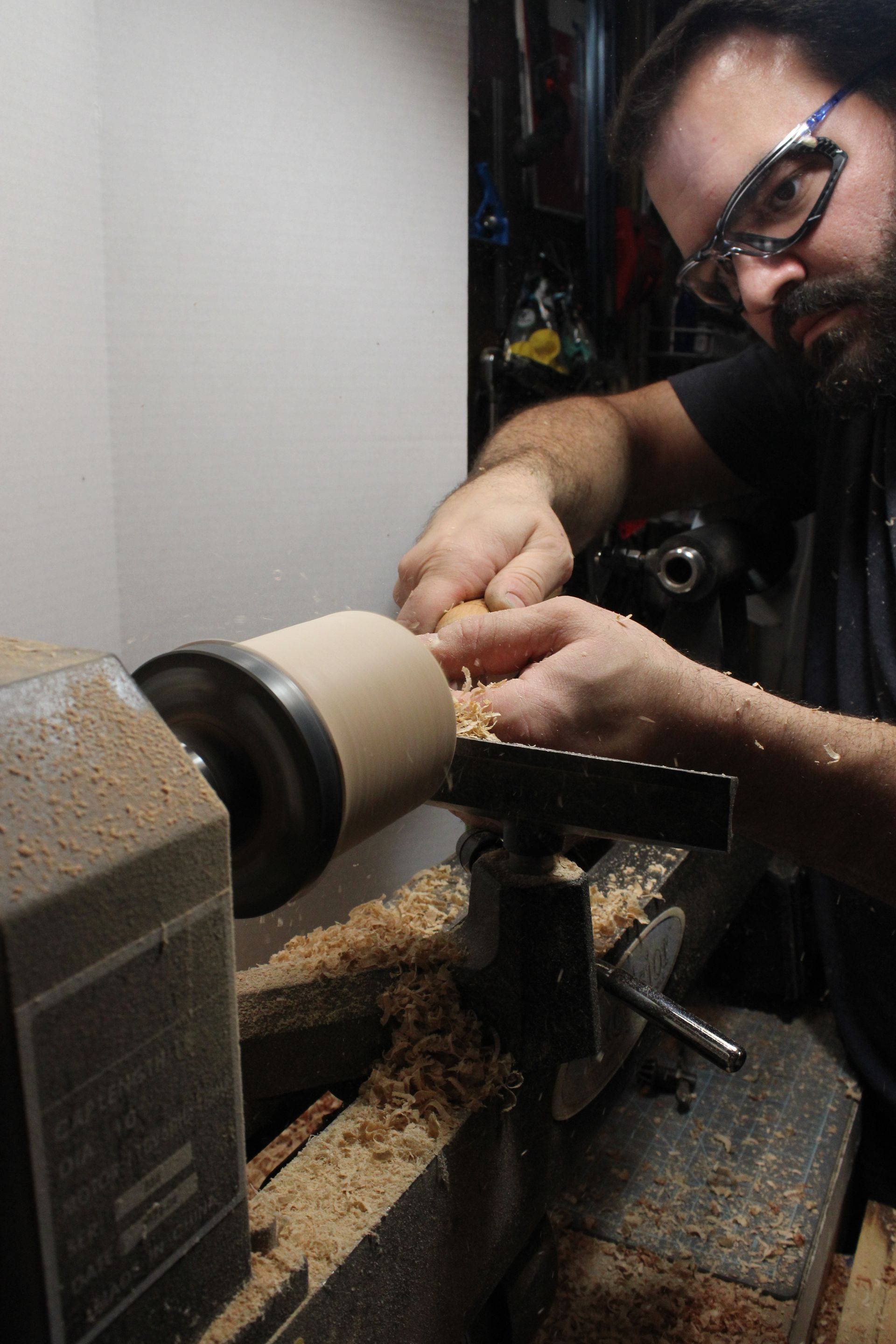 a man cutting the inside of a wooden bowl on a lathe