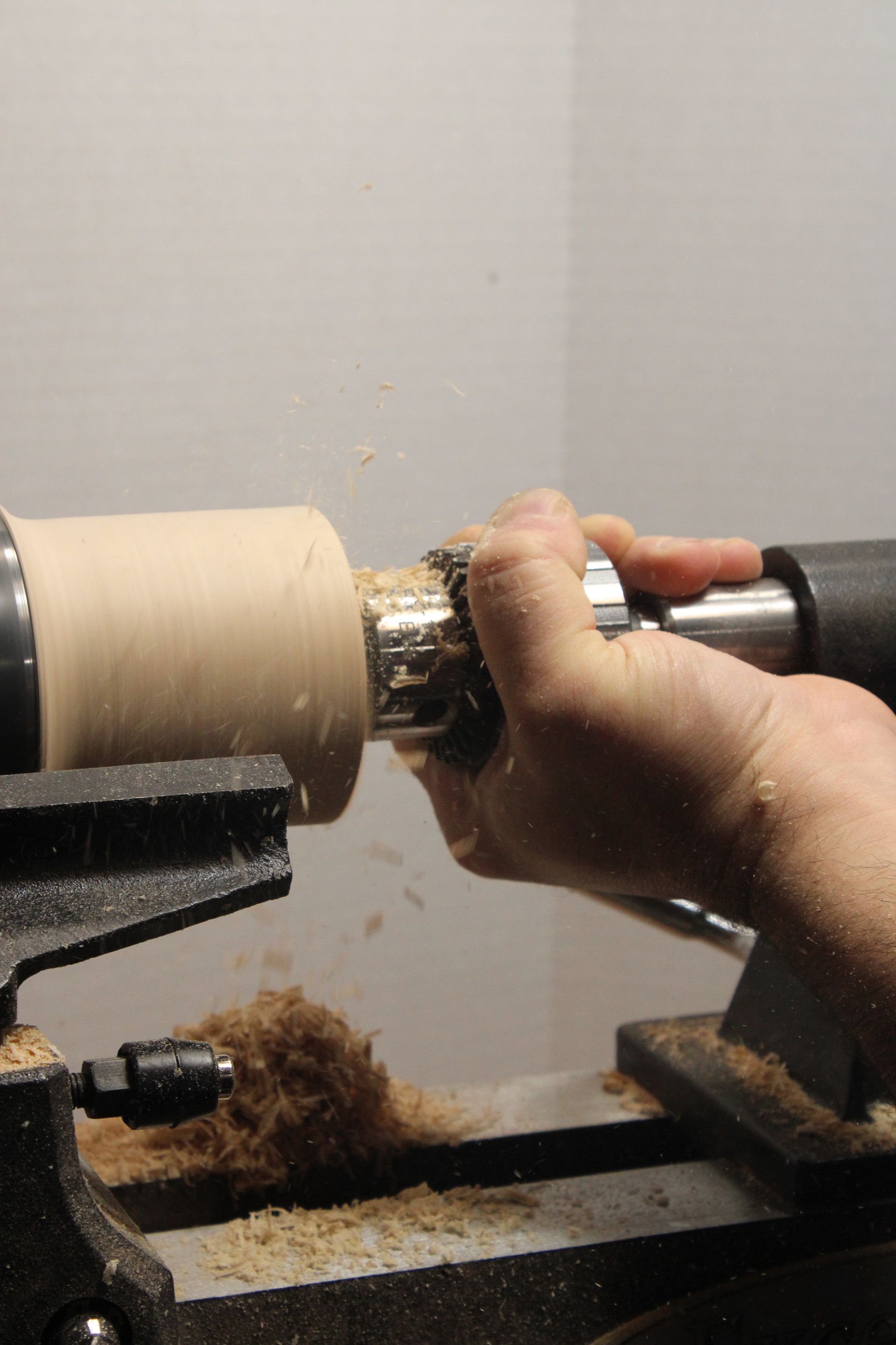 using a tool to bore out the center of a wooden bowl on a lathe