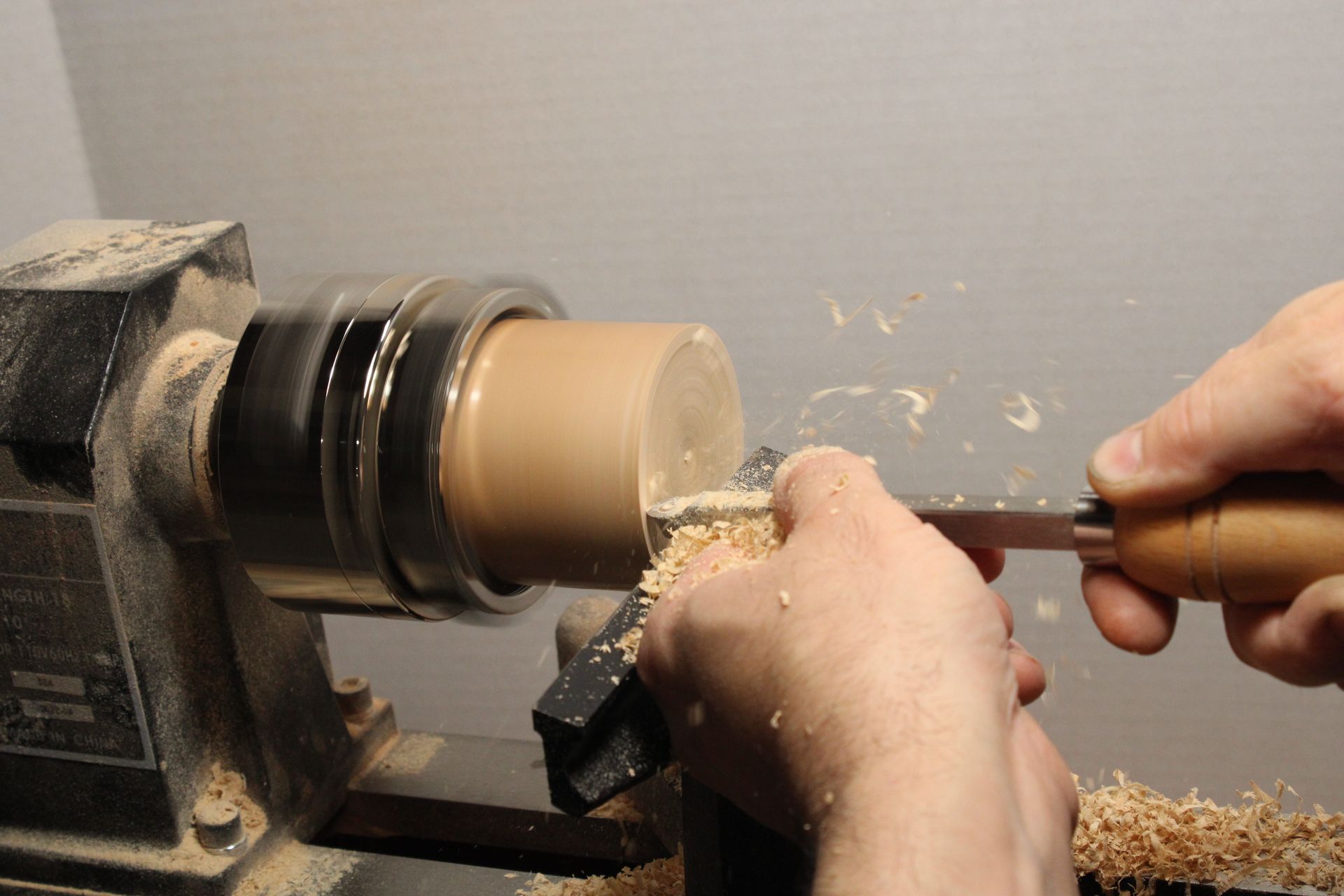 trimming the bottom of a wooden bowl on a lathe with a sharp tool