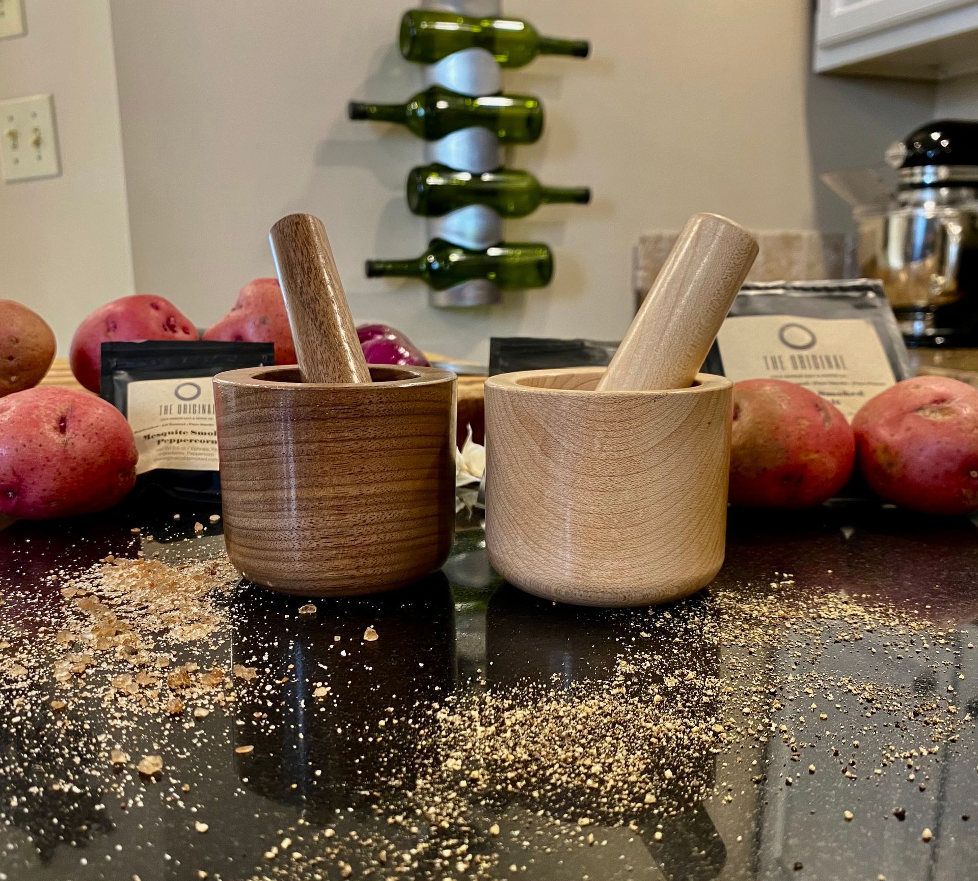 two mortar and pestles on a counter with red potatoes and seasoning packets and ground pepper sprinkled on the counter