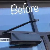 A black hydraulic door closer mounted on the inside of a glass door with a metal frame, labeled 