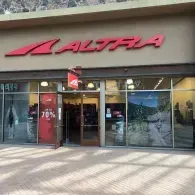 Storefront for an Altra footwear shop with glass doors, large windows, and a prominent red company logo.