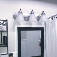 A three-light vanity fixture with frosted glass shades mounted above a black-framed bathroom mirror.