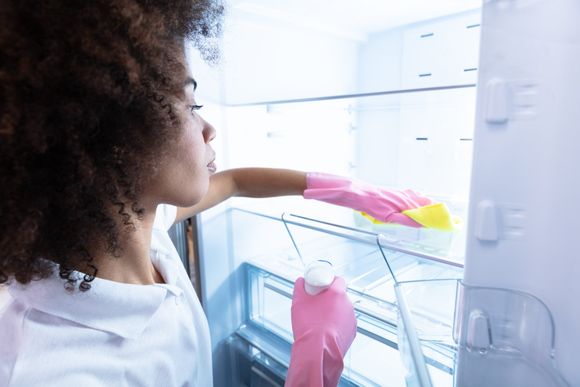 Young Woman Wearing Gloves Cleaning Refrigerator