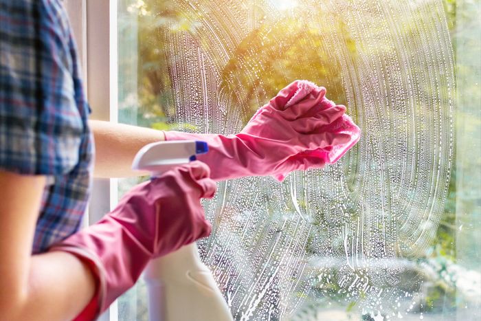 A woman clean a window pane with a rag and soap suds