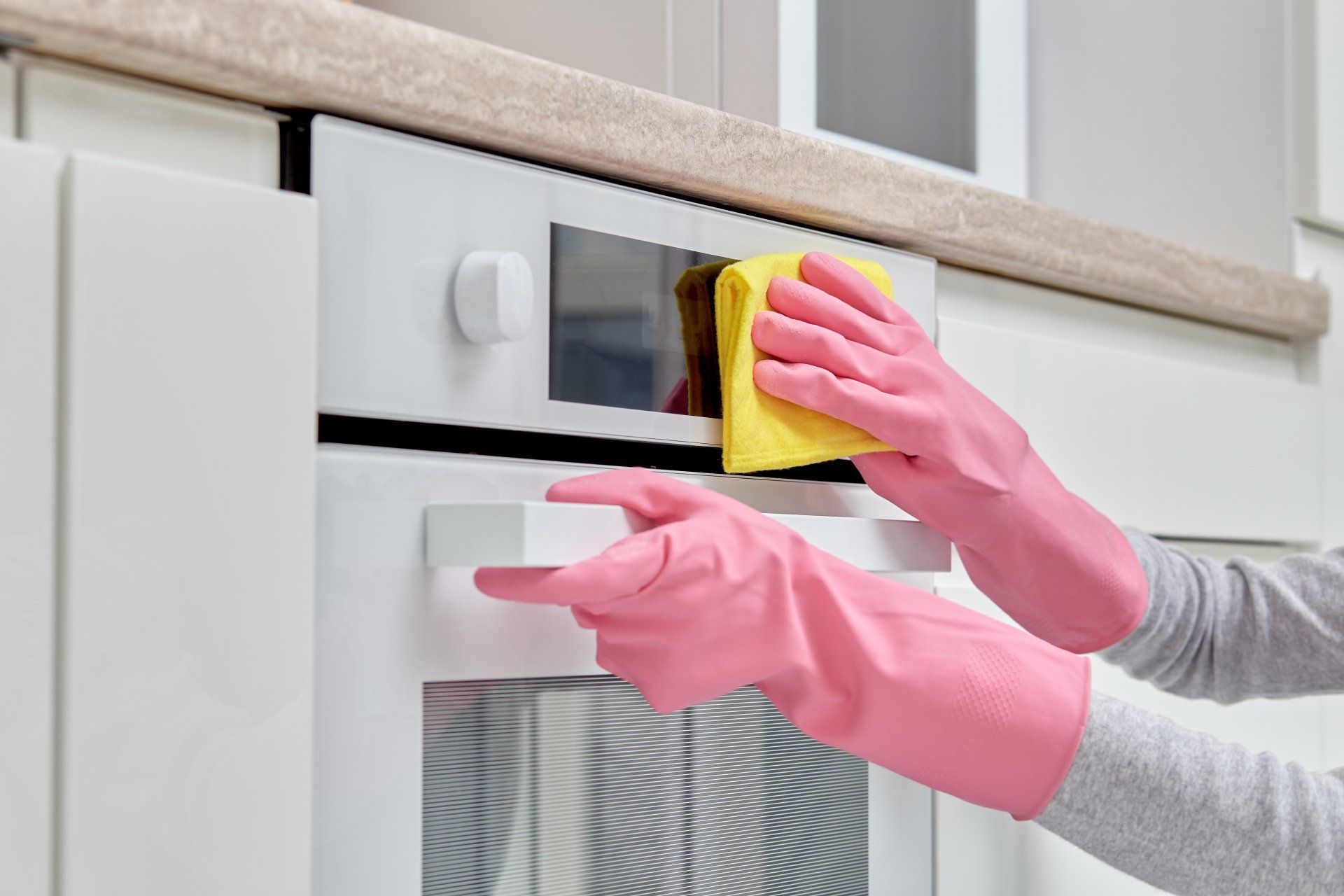 Women's hands in pink rubber gloves doing cleaning in the kitchen.
