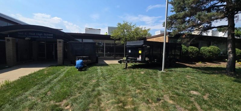 Exterior view of a building with a blue scooter parked on the lawn. The sky is blue with a few clouds.