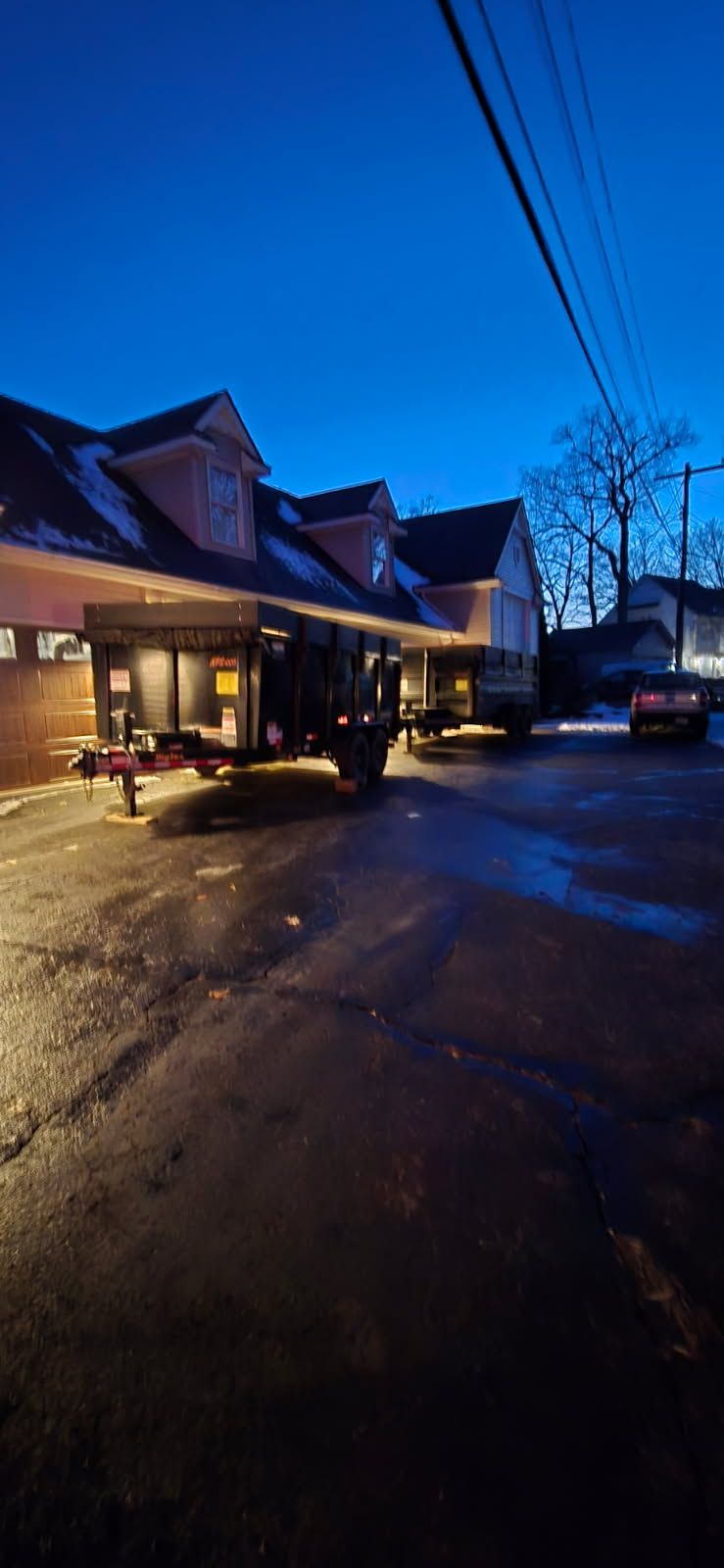 Building exterior at dusk with a vehicle parked in front. Dark blue sky.