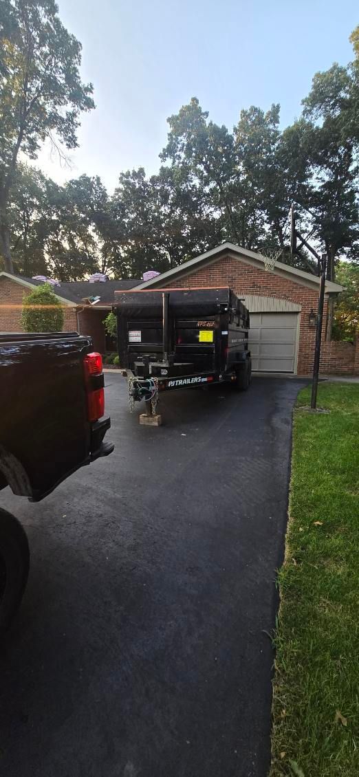 A black truck is parked in front of a house with a trailer in the driveway.