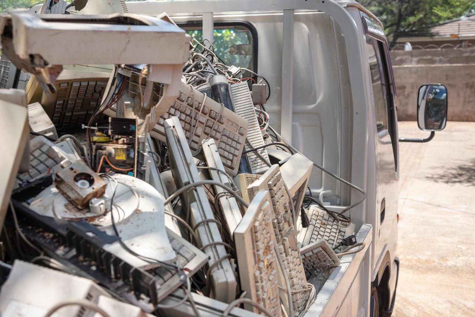 White truck bed filled with discarded computer parts, including keyboards, cables, and monitors.