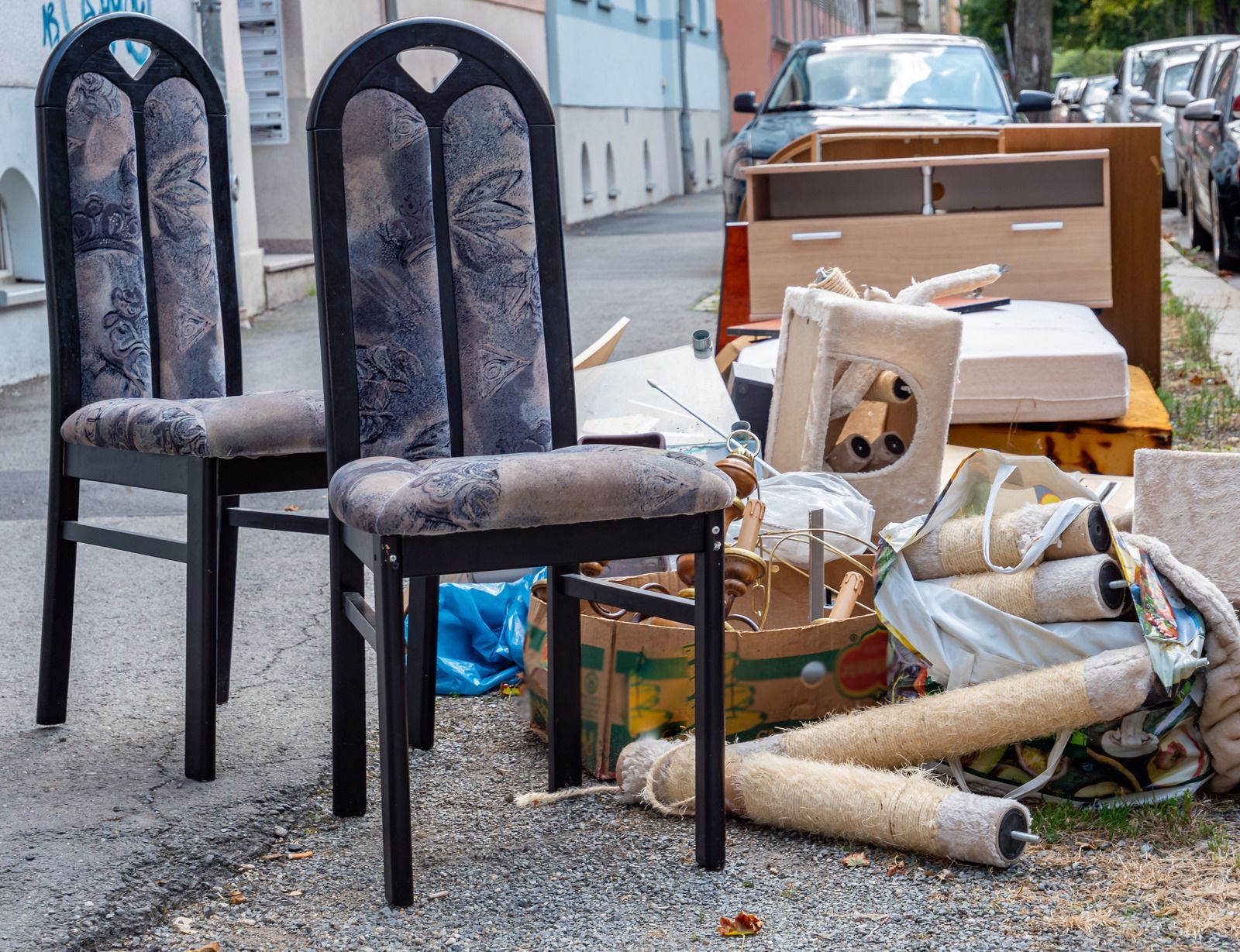 Two chairs and other discarded household items on a street.