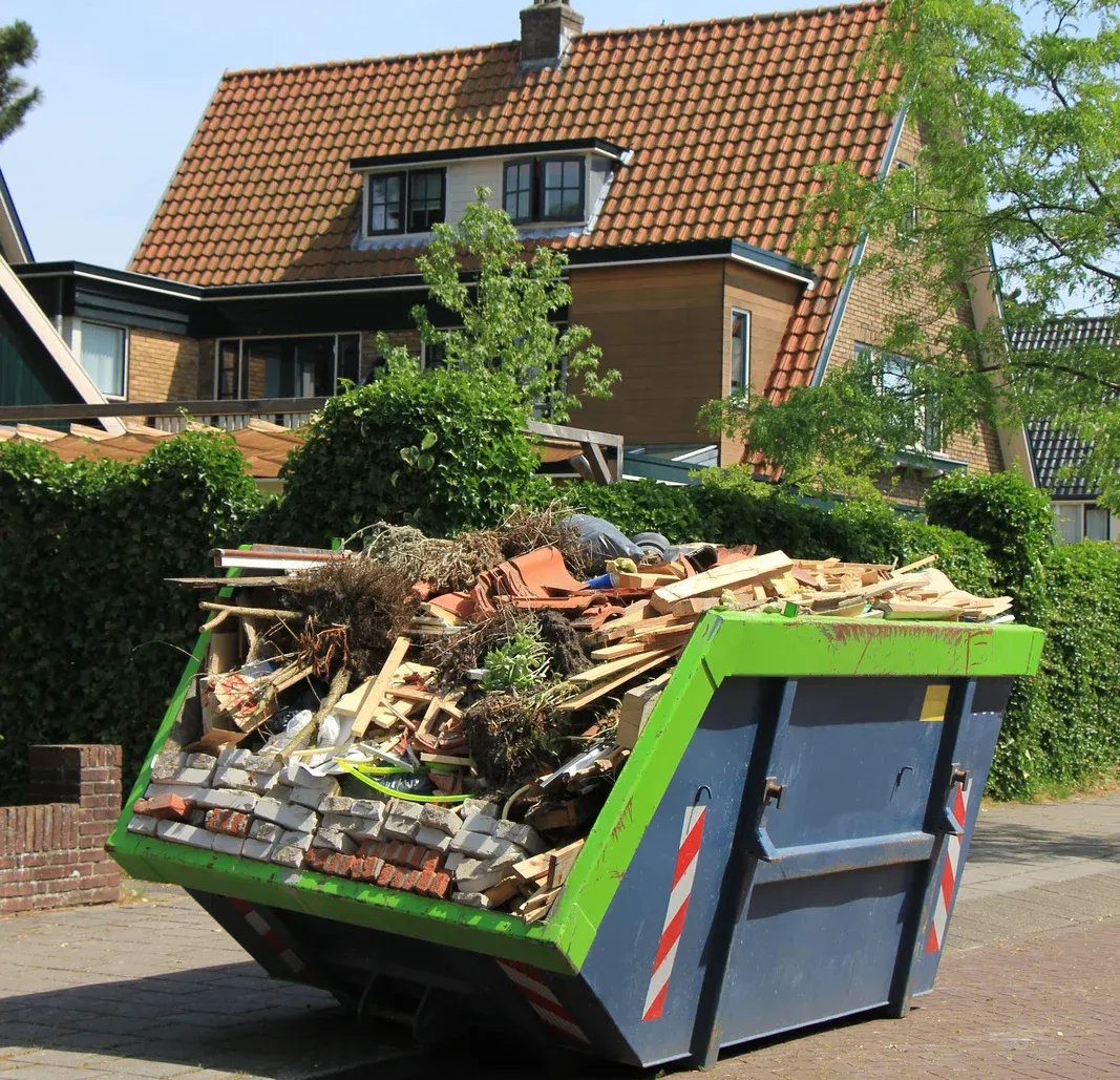 Dumpster overflowing with construction debris in front of a house.