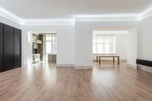 Modern, open-concept interior with wood floors, white walls, and dark cabinetry. Kitchen and dining area visible.