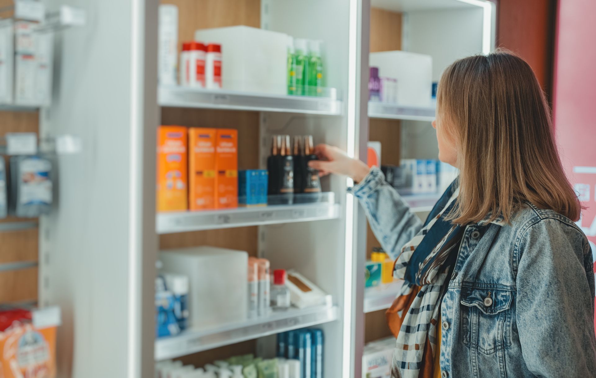 Una mujer está mirando un estante en una farmacia.