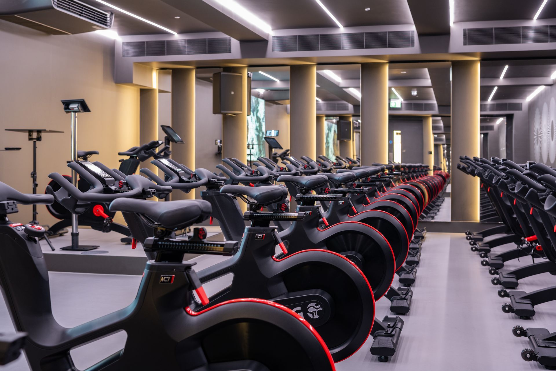 A row of exercise bikes are lined up in DSQ gym with a huge mirror.