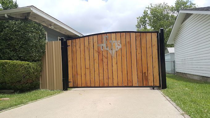 A black fence with a sliding gate in a driveway.