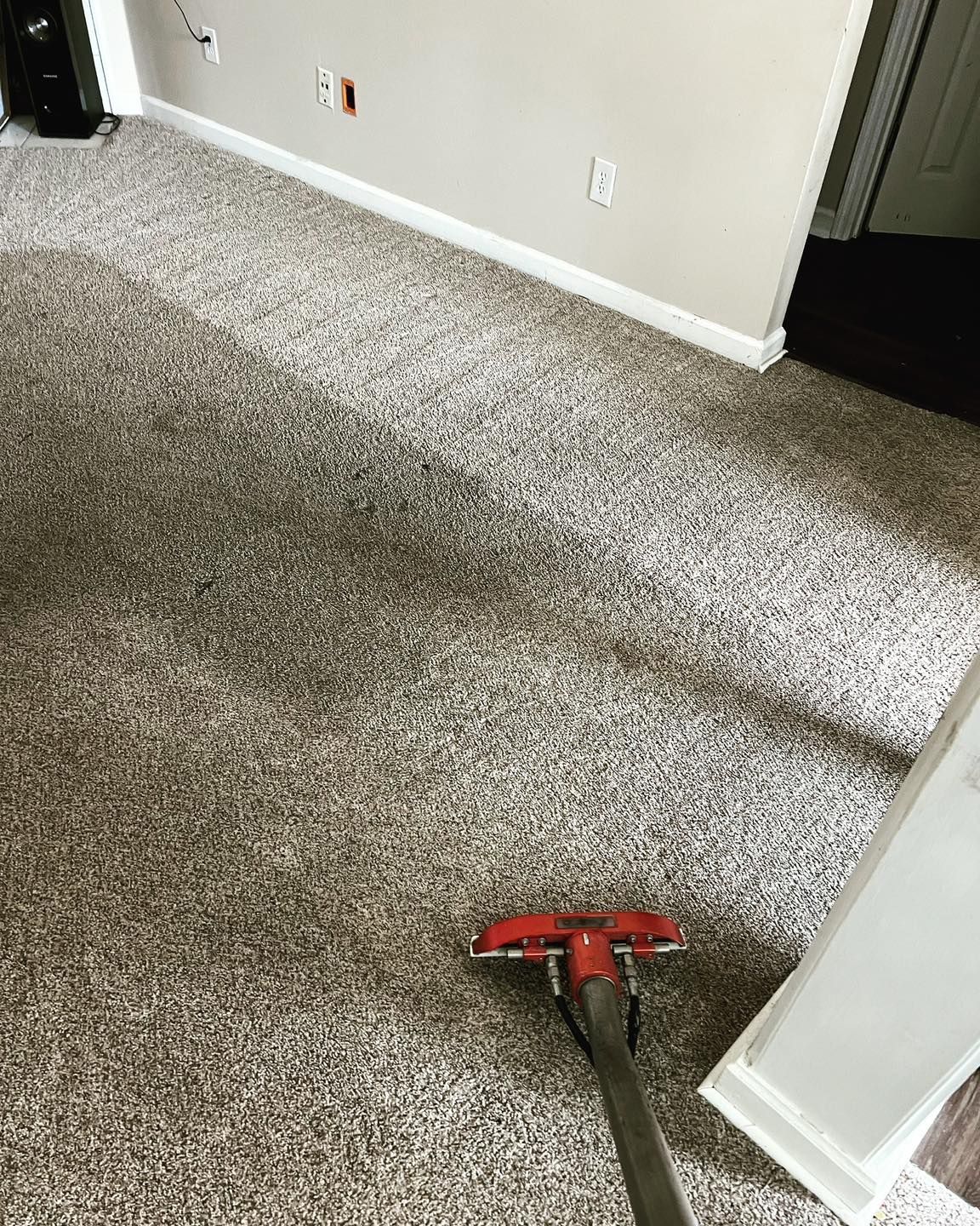 A vacuum cleaner is cleaning a carpet in a living room.