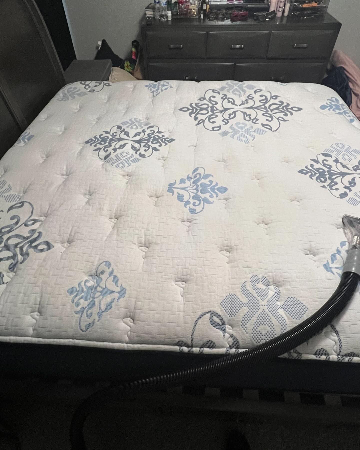 A mattress is being cleaned with a vacuum cleaner in a bedroom.
