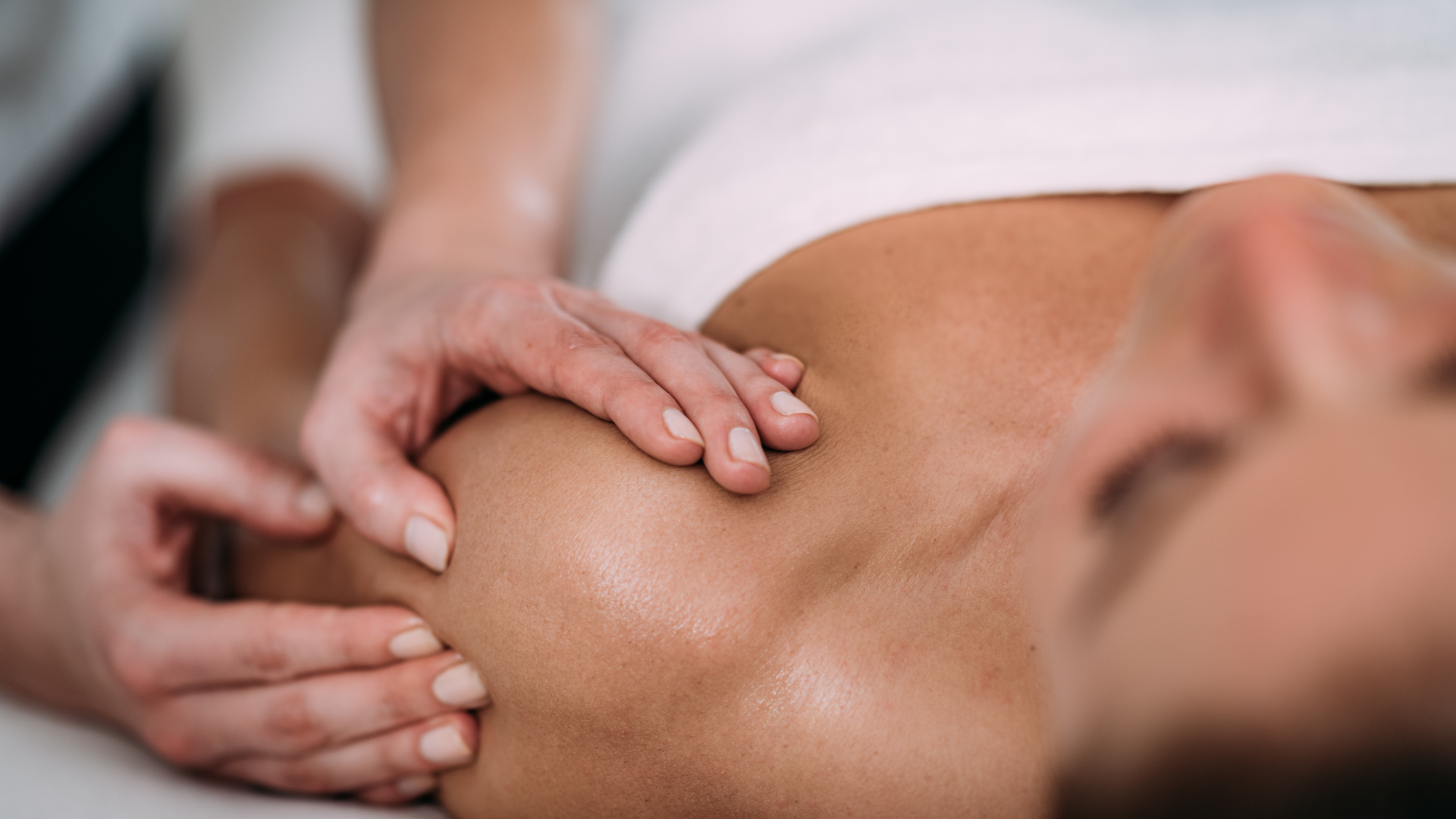 A woman is getting a massage on her shoulder at a spa.