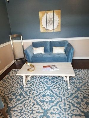 A living room with a blue couch and a white coffee table.