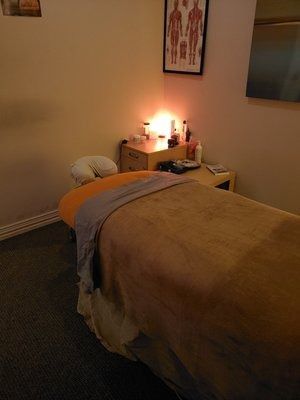 A massage table in a room with a picture on the wall above it.