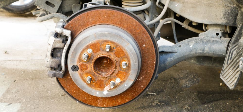 Brake service in Lake Mills, WI by Topel's Towing and Repair. Image of a rusty brake rotor on a vehicle, illustrating common issues with brake rust and the need for professional maintenance and repair services.