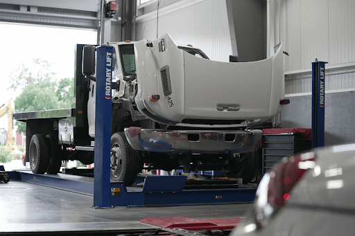 Medium duty truck repair and service in Lake Mills, WI with Topel’s Towing and Repair. Image of white medium duty fleet truck on lift in shop with hood open for repair services in shop.
